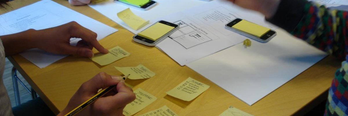 Multiple people at a table sketching on PostIt notes